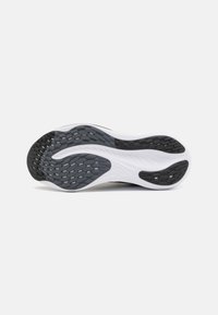 Suola di scarpa sportiva con un motivo in gomma nera testurizzata e intersuola in schiuma bianca, caratterizzata da un design curvo per una maggiore flessibilità.