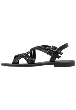 Black flat sandals with crisscross straps featuring multicolored glitter accents, a buckle closure, and a textured sole.