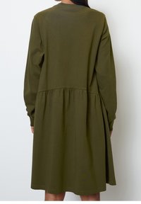 Zielono-oliwkowa sukienka z długim rękawem z miękkiego materiału, z okrągłym dekoltem, zgromadzonym w talii i rozkloszowanym dołem, o prostym wzornictwie, bez wzorów.