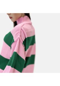 Suéter a rayas rosa y verde con cuello alto, hecho de tejido de punto, con acentos de canalé y costuras de hombro pronunciadas.