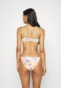 Conjunto de biquíni floral com um top multicolorido com alças ajustáveis e uma parte de baixo de cintura baixa com um padrão semelhante. Tecido de textura suave.