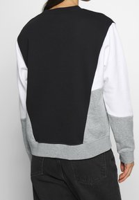 Kleurblok sweatshirt met zwarte, witte en grijze panelen. Zacht, struktureer materiaal met een ronde hals en geribbelde mouwen.
