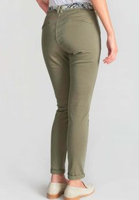 Olijfgroene taps toelopende broek met opgerolde cuffs, met een gepatternde tailleband. Gemaakt van een gladde stof, voorzien van achterzakken.