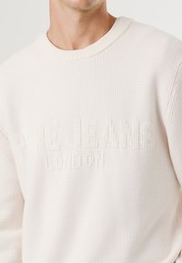 Suéter branco de malha com decote redondo canelado, apresentando texto elevado "PEPE JEANS" e "LONDRINA" na mesma cor na parte da frente.