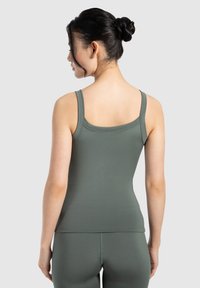 Ciemnozielony top na ramiączkach z gładkiego, elastycznego materiału. Posiada dopasowany krój, szerokie ramiączka i zaokrąglony dekolt.