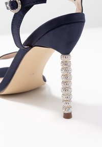 Námořnické saténové sandály na vysokém podpatku s zdobeným, cylindrickým podpatkem a sponou, s hladkým nártem a béžovou podrážkou.