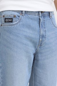 Vaqueros de mezclilla azul claro con un corte clásico, que presentan un diseño de cinco bolsillos, un sutil desgaste y una etiqueta con el logo negro en la parte trasera de la cintura.