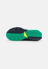 Semelle de chaussure de course avec une semelle verte et bleu foncé, avec un logo triangulaire jaune près de la partie centrale.
