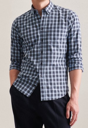 Camisa a cuadros en azul claro y marino con collar de botón, mangas largas arremangadas, con un bolsillo en el frente y un dobladillo curvado.