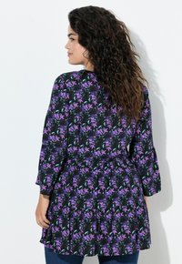 Black floral dress featuring purple and teal flowers, long sleeves, a belted waist, and a flared skirt with ruffles at the hem.