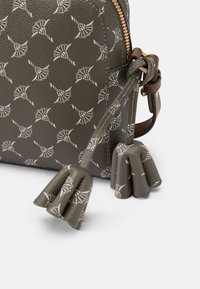 Borsa in pelle verde con motivo, dalla forma rotonda, con cerniera metallica e accenti decorativi a frange. Presenta disegni bianchi in rilievo su tutta la superficie.