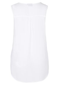 Blusa sin mangas blanca con una textura suave. Presenta un suave pliegue en la parte posterior y un dobladillo redondeado y ligeramente alargado.