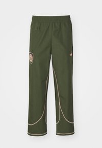 Grüne Hose mit elastischem Bund, seitlichen Taschen, hellbraunem Nähten und einem Logo-Patch am linken Oberschenkel. Gerade Beinform.