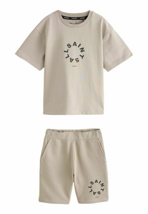 Beige t-shirt og shorts sæt i bomuldsblanding. T-shirten har et mørkt cirkel-logo. Shortsene har sidelommer og elastisk talje.