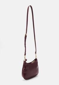 Burgundy läder axelremsväska med minimalistisk design, guldhardware och justerbar rem. Slät textur och dragkedjestängning.