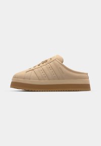 Bársonyos, napbarna slip-on sportcipő kerek orral, vastag talppal, texturált felsőrésszel és három függőleges csíkkal az oldalon.
