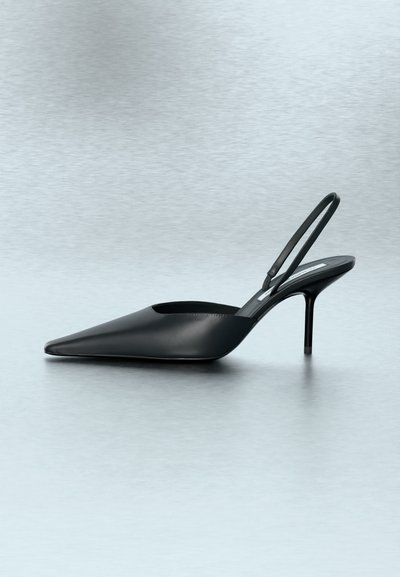 Μαύρο δερμάτινο γοβάκι με μυτερή μύτη, λουράκι και λεπτό τακούνι στιλέτο σε μεταλλική γκρι επιφάνεια.