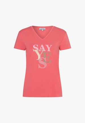 Korallenfarbenes T-Shirt mit kurzen Ärmeln und V-Ausschnitt, vorne mit übereinanderliegenden "SAY YES"-Schriftzügen in Hellrosa, Beige und Braun.