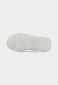 Λευκή σόλα παπουτσιού από καουτσούκ με ανάγλυφο υφή που δείχνει γράμματα, όπως τα "K" και "C", τοποθετημένα σε επαναλαμβανόμενο σχέδιο.