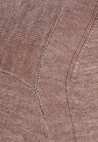 Tessuto a maglia in una calda tonalità taupe, caratterizzato da un motivo testurizzato con diverse dimensioni dei punti e bordi lisci, che mette in evidenza un aspetto morbido e accogliente.