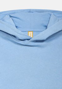 Helles blaues Hoodie mit weicher Textur, lockerem Schnitt und einfachem Design. Enthält ein kleines gelbes Etikett am Hals.