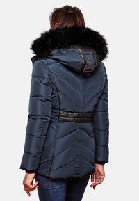 Gevoerde marineblauwe jas met een zwarte faux fur capuchon, chevron-quiltpatroon, leren accenten en een aansluitende taille, weergegeven vanaf de achterkant.