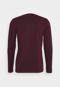Langmouwige bordeauxrode shirt gemaakt van gladde stof, met een eenvoudige ronde halslijn en een eenvoudig ontwerp zonder zichtbare logo's of patronen.