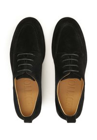 Chaussures en suède noir avec un bout arrondi, cinq œillets et lacets foncés. L'intérieur est beige avec des motifs de marque en relief. Semelle plate.