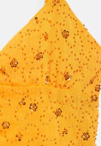 Tissu jaune avec de petites perles ambres brillantes cousues en formes de fleurs et motifs dispersés sur un matériau léger texturé.