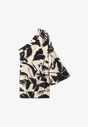 Top beige asymétrique avec manche large évasée et motif feuilles tropicales noires.