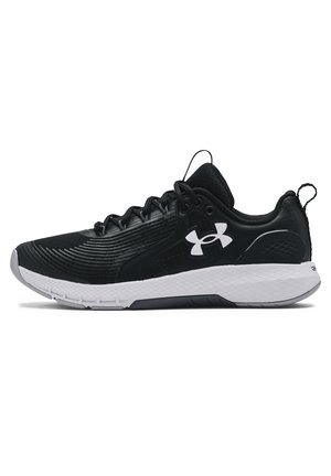 Chaussure de sport basse noire avec semelle blanche texturée et logo Under Armour sur le côté, avec lacets et languette au talon.