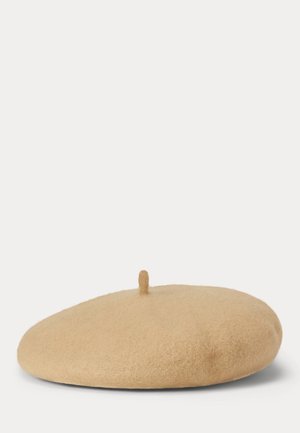 Béret en laine beige avec une petite tige en tissu sur le dessus, présenté sur un fond blanc uni.