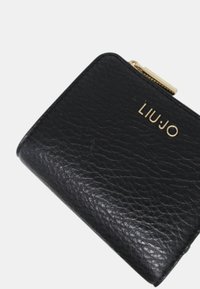 Portafoglio in pelle nera con una finitura testurizzata. Presenta una cerniera in tono oro e il nome del marchio "LIU JO" impresso sulla parte anteriore.