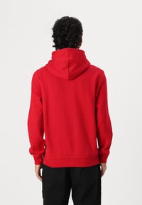 Rød hettegenser med stor hette, rutete mansjetter og midjebånd. Stoffblanding av bomull, glatt tekstur og enkelt design.