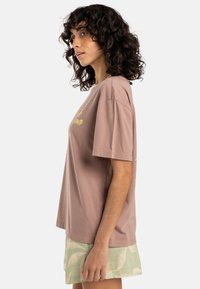 Licht mauve katoenen t-shirt met een ontspannen fit, korte mouwen en gele tekst. Gecombineerd met mintgroene gestreepte shorts.