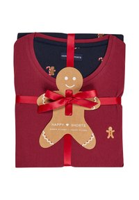 Conjunto de pijama rojo con una camisa azul oscura que presenta un patrón de bastones de caramelo. Presentado con una cinta roja y una etiqueta de hombre de jengibre.