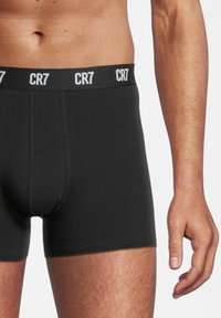 Zwarte boxershorts met een elastische tailleband met het witte "CR7" logo, gemaakt van een gladde, rekbare stof met minimale stikdetails.