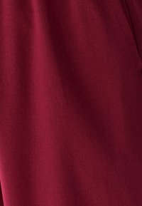 Burgundska tkanina, ki prikazuje gladko teksturo s fino tkanino. Preprost dizajn brez izrazitih vzorcev ali poudarkov.