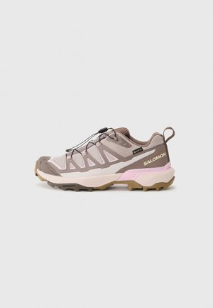Lichte wandelschoen in lichtroze en taupe. Beschikt over een bovenwerk van mesh, rubberen zool en elastische veters met toggle. Logo op de hiel.