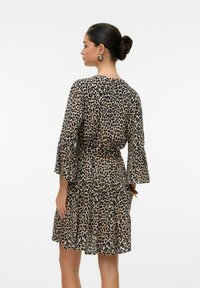 Robe imprimée léopard en beige et noir, avec des volants en couches, des manches évasées et une taille cintrée. Matière légère et fluide.