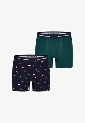 Zwei Paare Herrenboxershorts. Eine ist dunkelgrün, die andere navyblau mit weihnachtlichen Mustern aus Bäumen und Zuckerstangen.