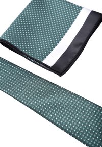 Cravatta e fazzoletto da taschino a motivi verde scuro con un piccolo design geometrico. I bordi sono neri con un accento bianco sul fazzoletto.