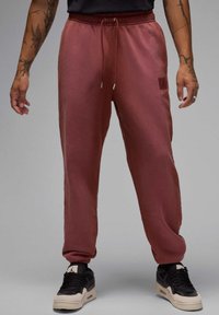 Bordeauxfarbene Jogginghose mit schmalem Schnitt, elastischem Bund und verstellbarem Kordelzug. Mit einem kleinen Logopatch und gerippten Bündchen.