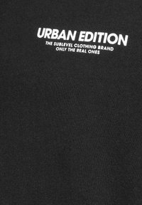 Schwarzes T-Shirt mit weißem Text: "URBAN EDITION DIE SUBLEVEL MODEMARKE NUR FÜR DIE ECHTEN." Glatte Textur, klassischer Rundhalsausschnitt.