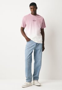 Lühikeste varrukatega T-särk, millel on roosa kuni valge gradient ja trükitud graafika. Ühitatud helesiniste teksade ja valgete tossudega.