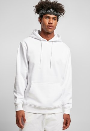 Hvid hoodie lavet af bomuldsblanding, med en frontlommesæk, snøre i hætten, ribbede manchetter og kant. Modellen står foran en grå baggrund.