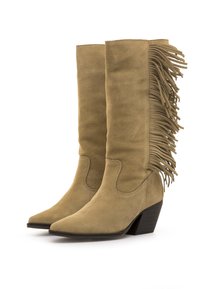 Botas de ante beige hasta la rodilla con detalles de flecos en el lateral exterior, puntera puntiaguda y tacón apilado para mayor estabilidad.