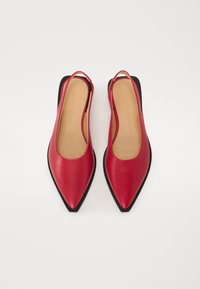 Scarpe slingback in pelle rossa con punta affusolata, suola piatta nera e texture liscia. L'interno è beige con marchio embossato.