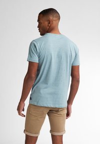 Light blue t-shirt with a textured pattern, short sleeves, and a crew neck. Paired with rolled-up khaki shorts.