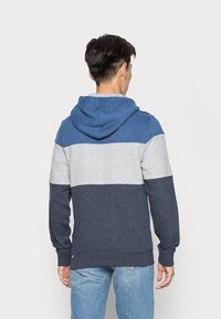 Hoodie met een kleurblokontwerp in lichtgrijs, marineblauw en blauwe secties. Gemaakt van zachte, gestructureerde stof met lange mouwen.